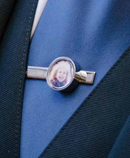 Silver photo tie clip with a child's photo on a blue tie